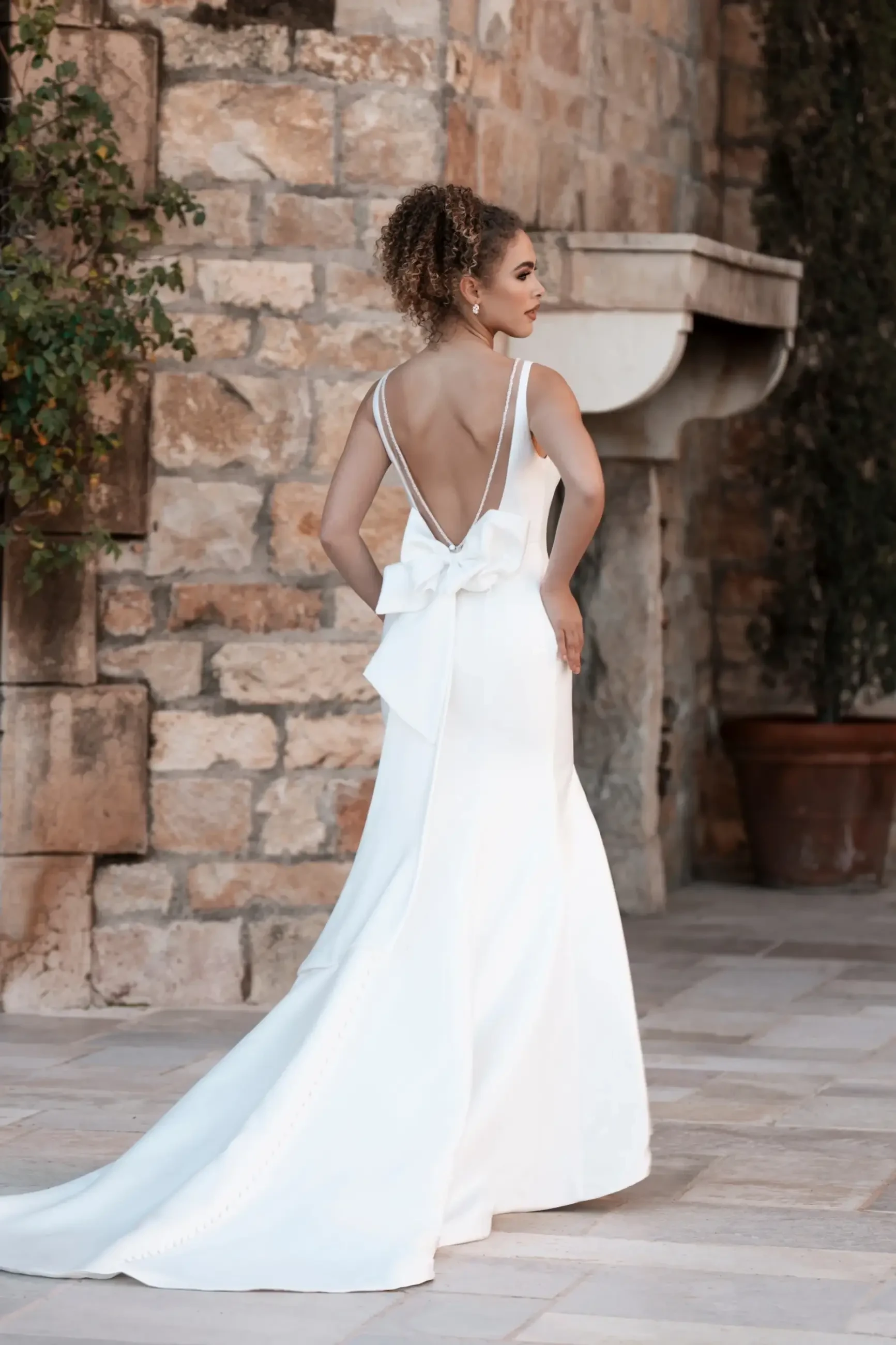 Model is wearing a fit-and-flare Mikado gown with a beaded illusion V-back and a bow at the back.