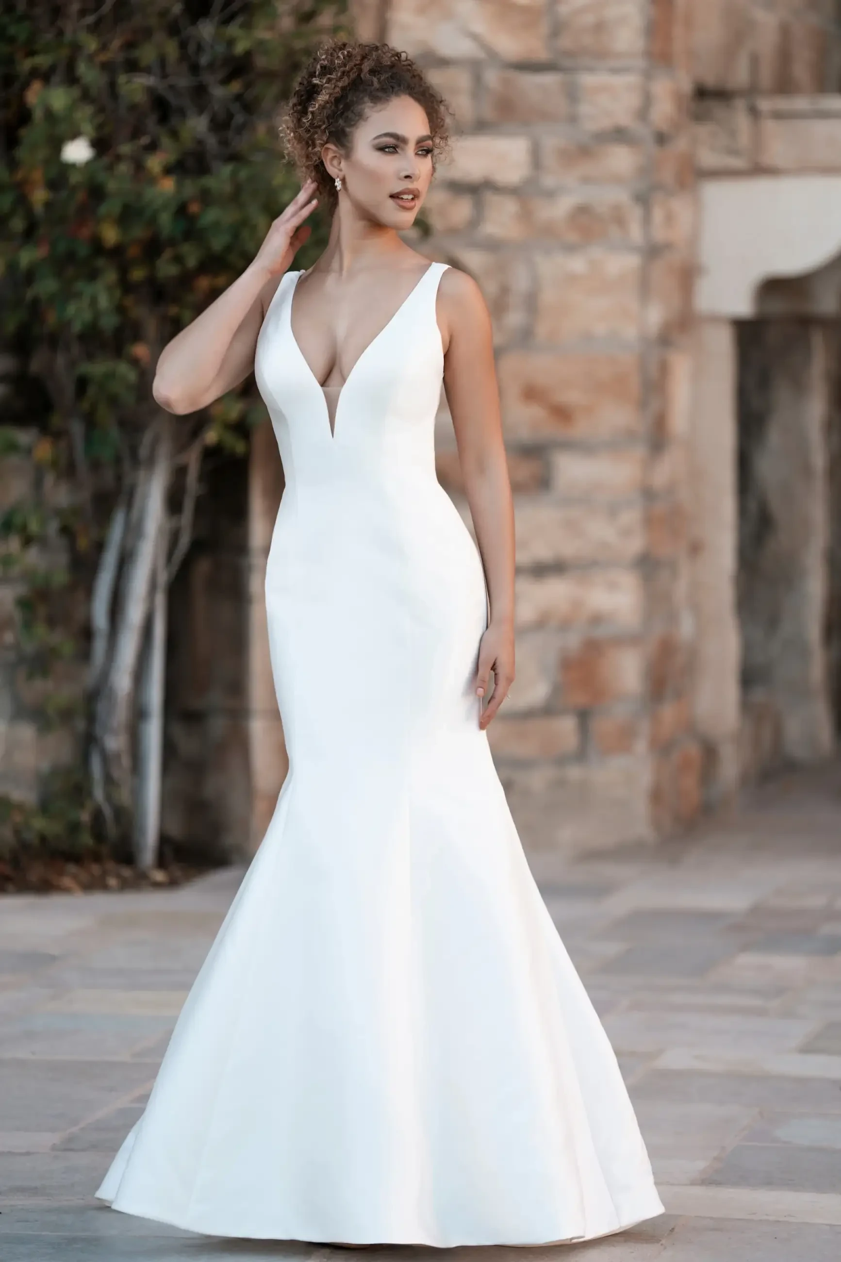 Model is wearing a fit-and-flare Mikado gown with a beaded illusion V-back and a bow at the back.