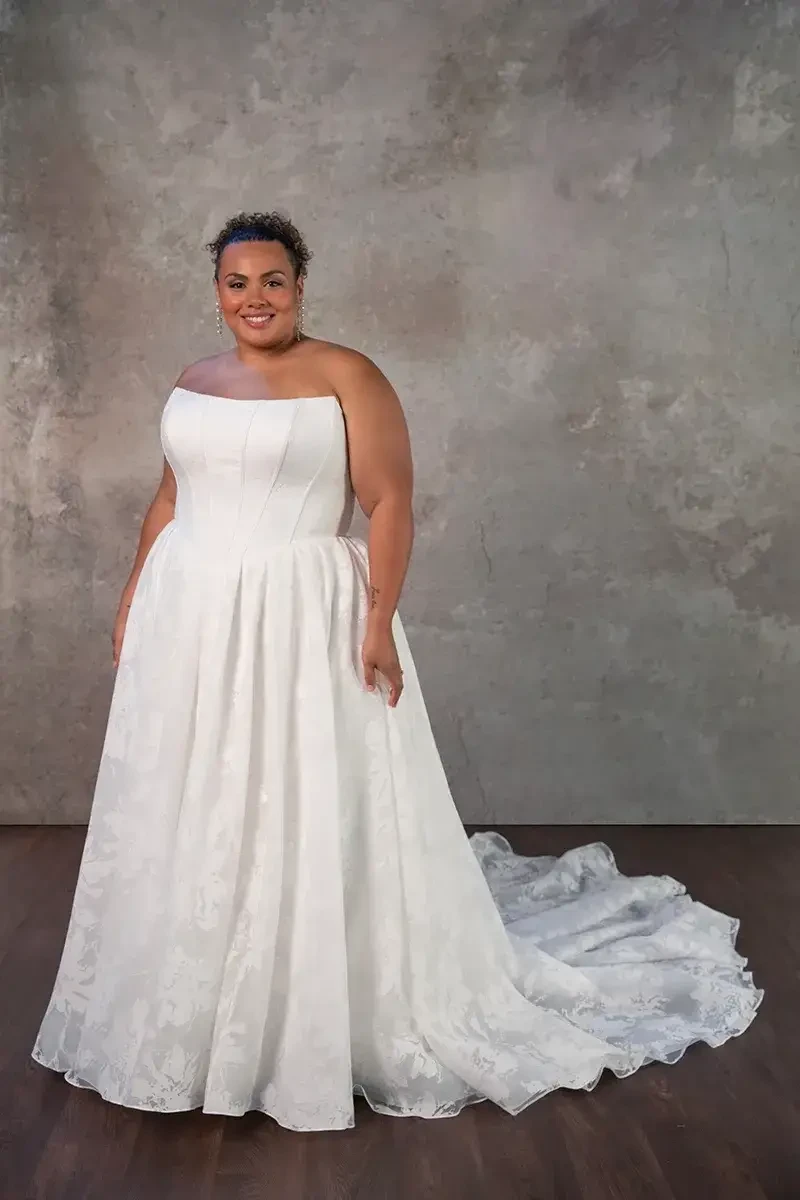 Model is wearing a strapless ball gown in organdy jacquard featuring a scoop neckline and full skirt.