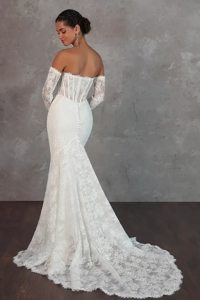 Model is wearing a strapless Chantilly lace column gown with a sweetheart neckline, exposed boning, and detachable sheer lace sleeves.